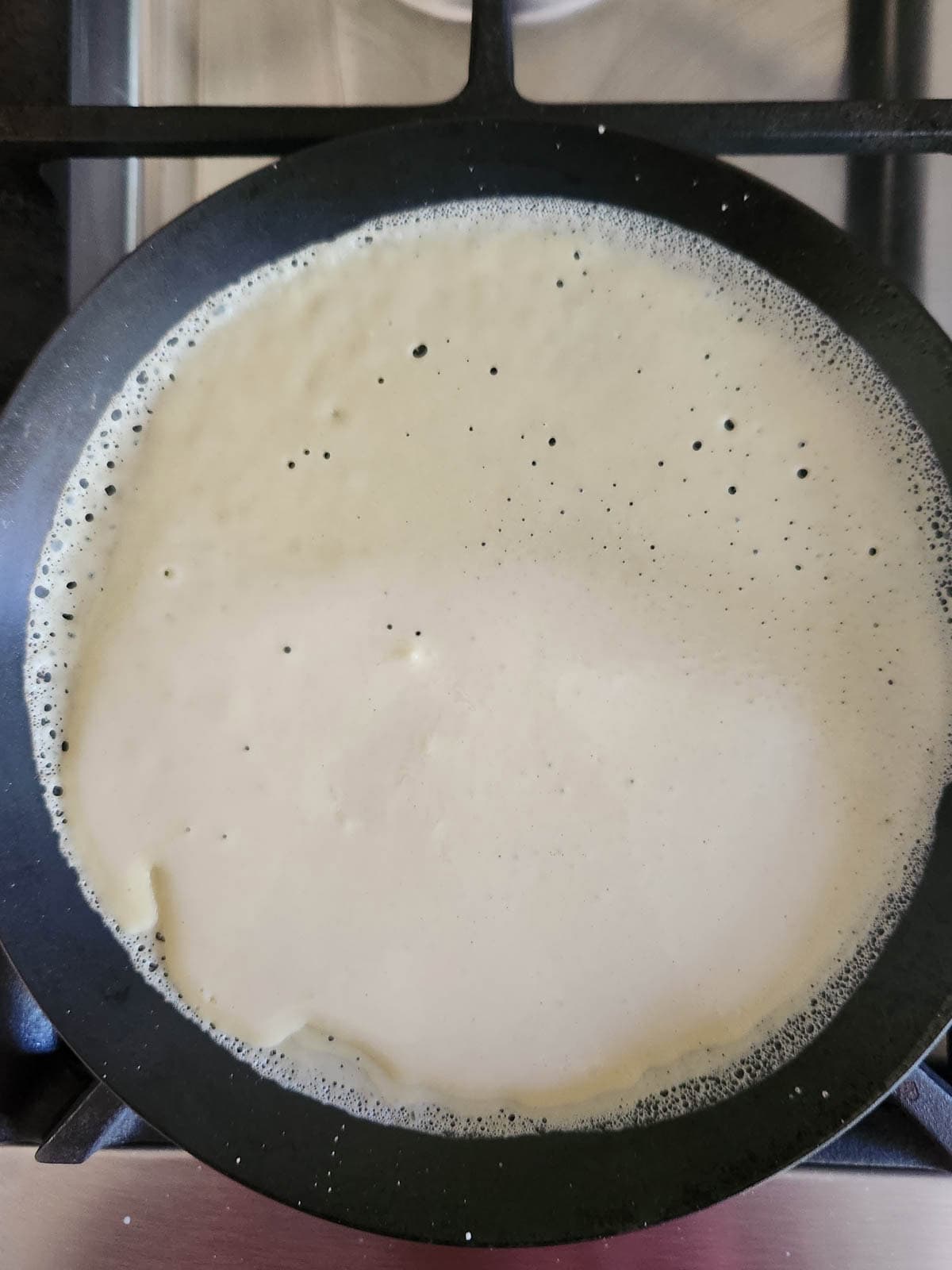 Overhead of crepe batter in a pan.
