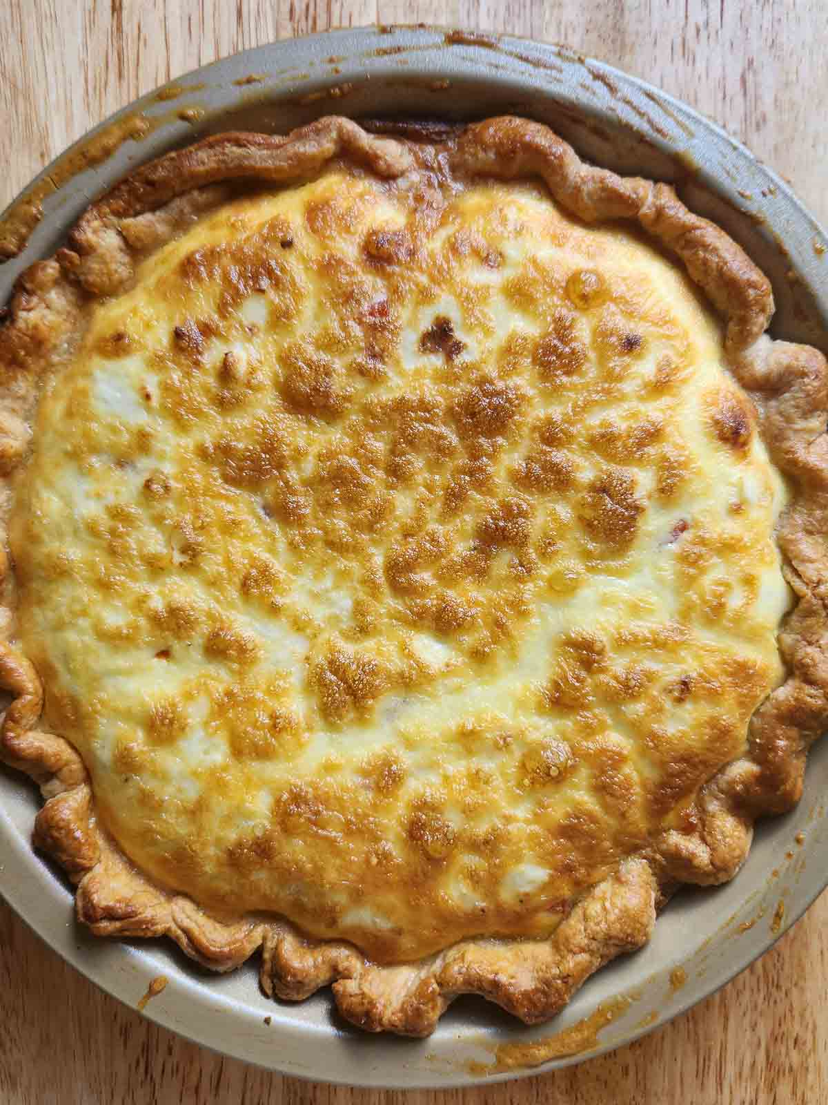 Overhead of cooked quiche in a metal pan.
