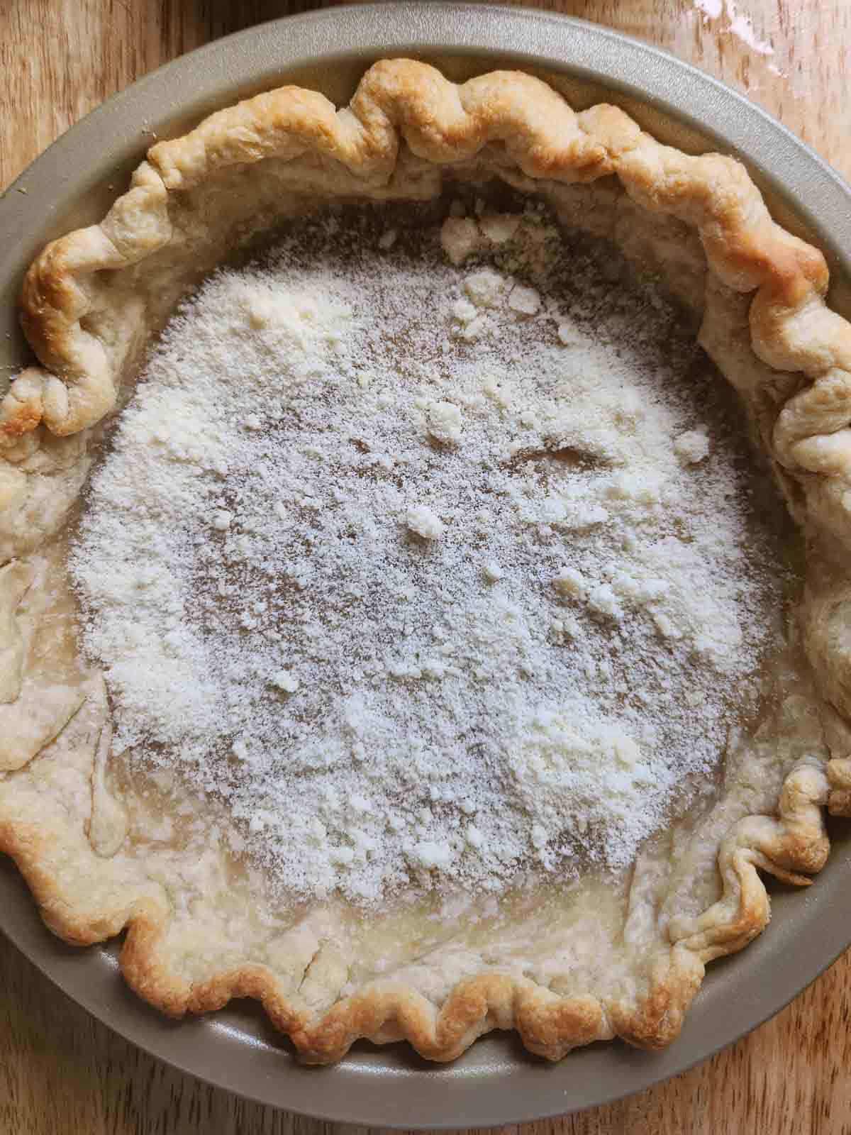 Overhead of quiche crust with Parmesan cheese on the bottom.
