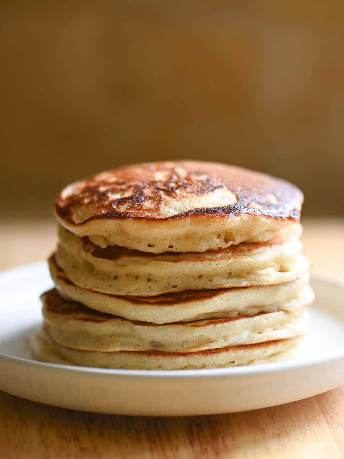 A stack of fluffy pancakes on a white plate.
