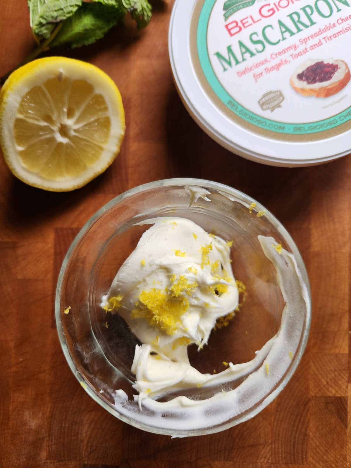 Mascarpone and lemon zest in a clear bowl.