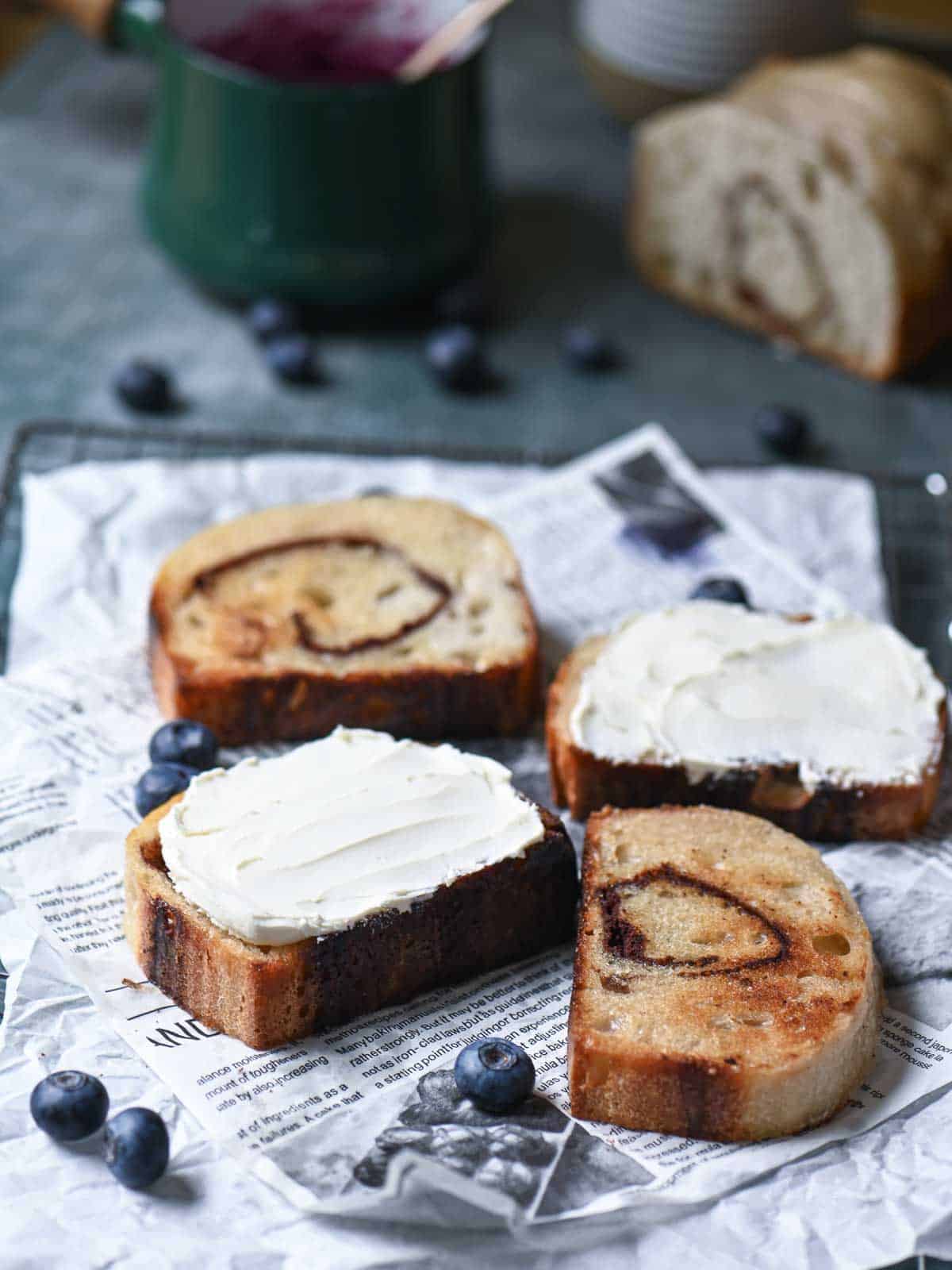 Four slices of toast with cream cheese spread on parchment paper.