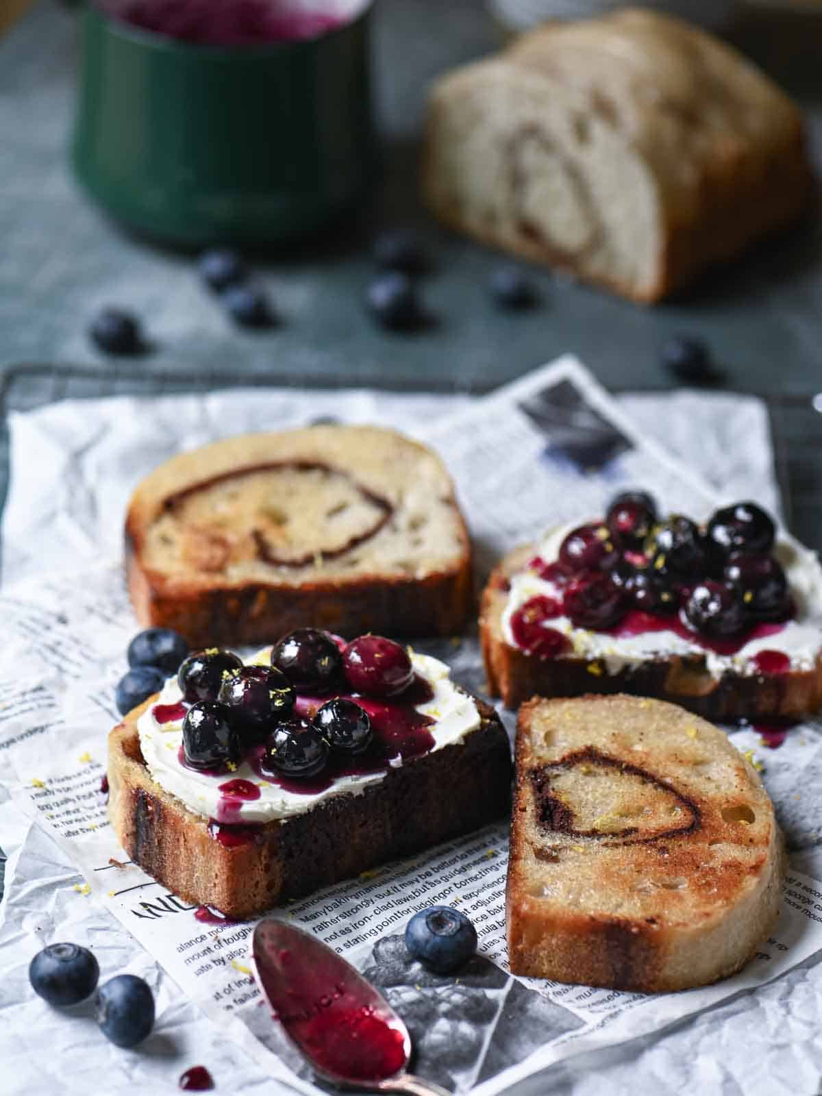 Blueberries on toast with cream cheese on top of parchment paper.