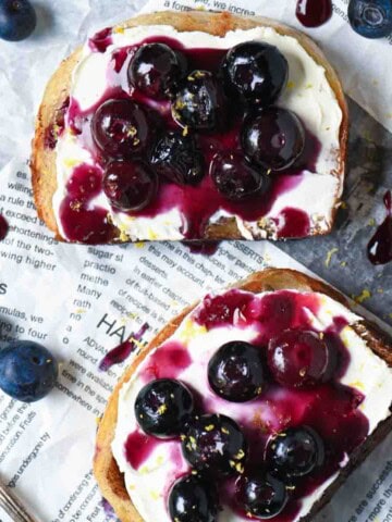 Overhead of 2 blueberry toasts with scattered blueberries around it.