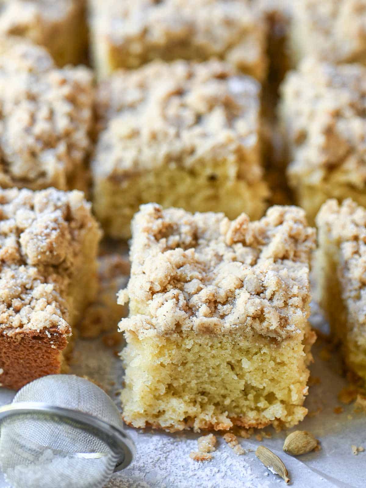 A square of coffee cake with crumb topping on parchment paper.