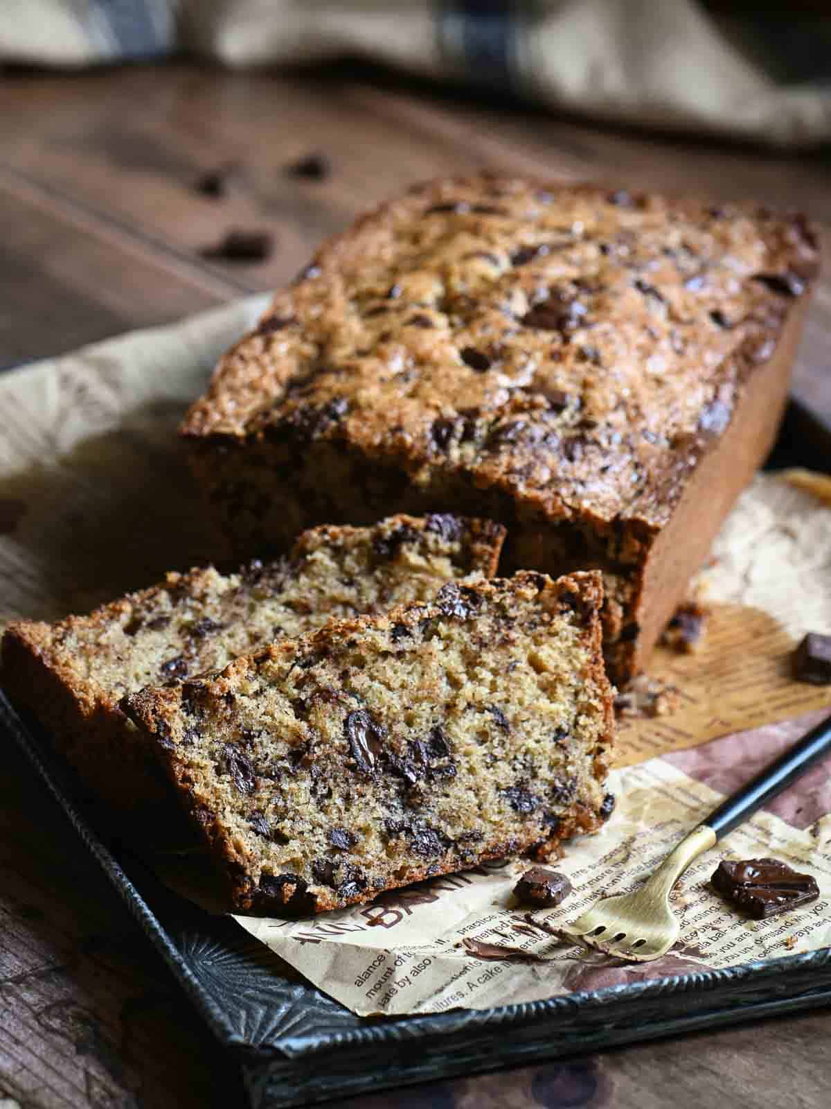 Chocolate chip bread cut with a few slices showing the inside on a wooden board.