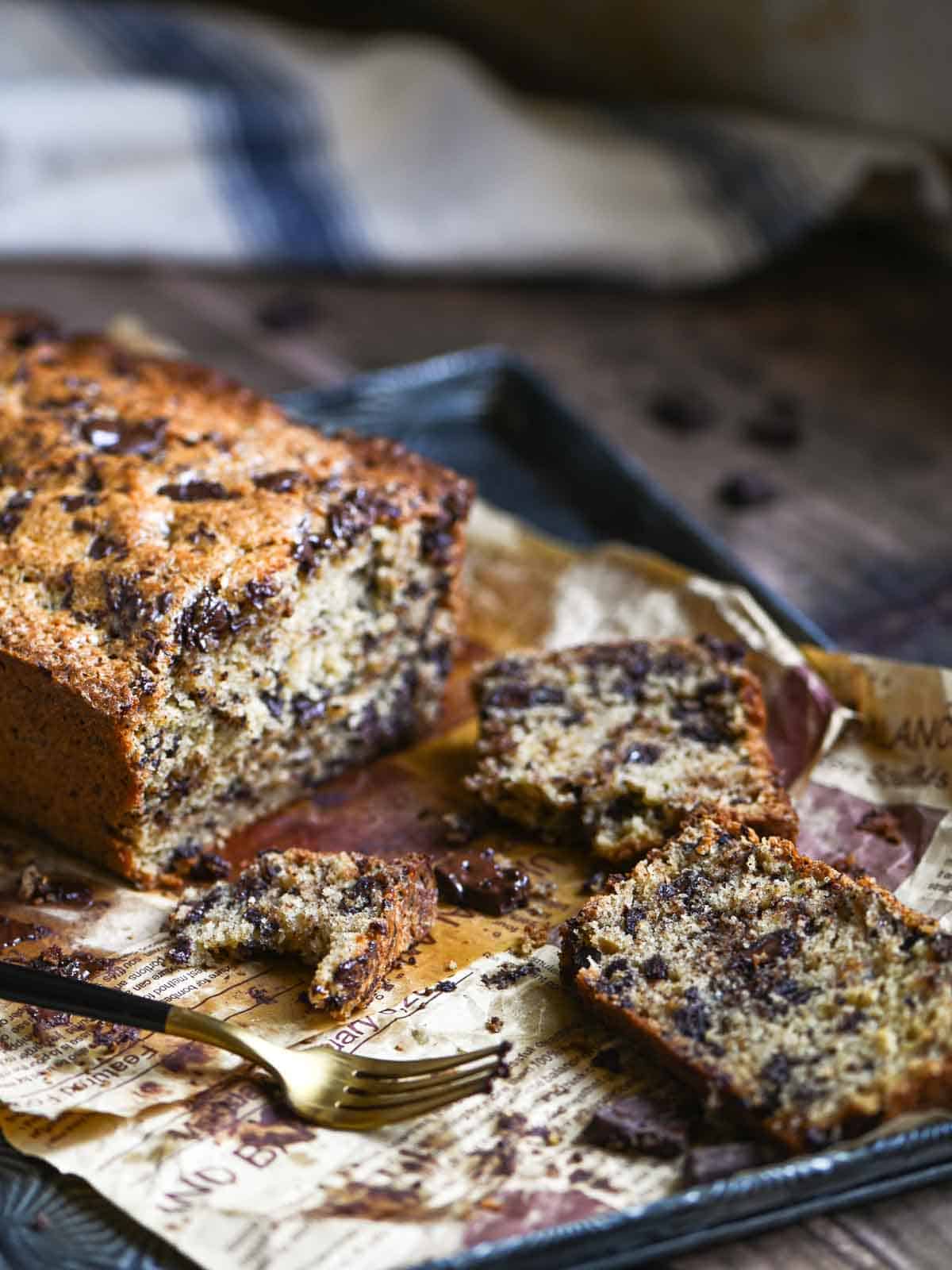 Slices of chocolate chip loaf cake sliced on a tray with a fork.