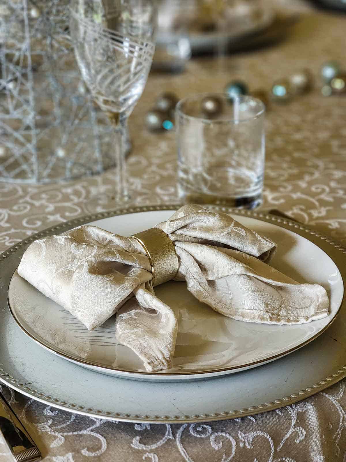 A grey napkin folded into a bow on a place setting.