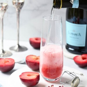 Prosecco being pured into a glass with plum puree.
