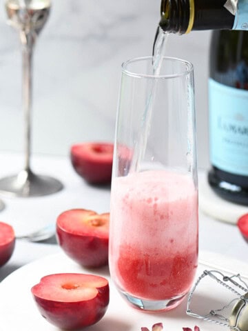 Prosecco being pured into a glass with plum puree.