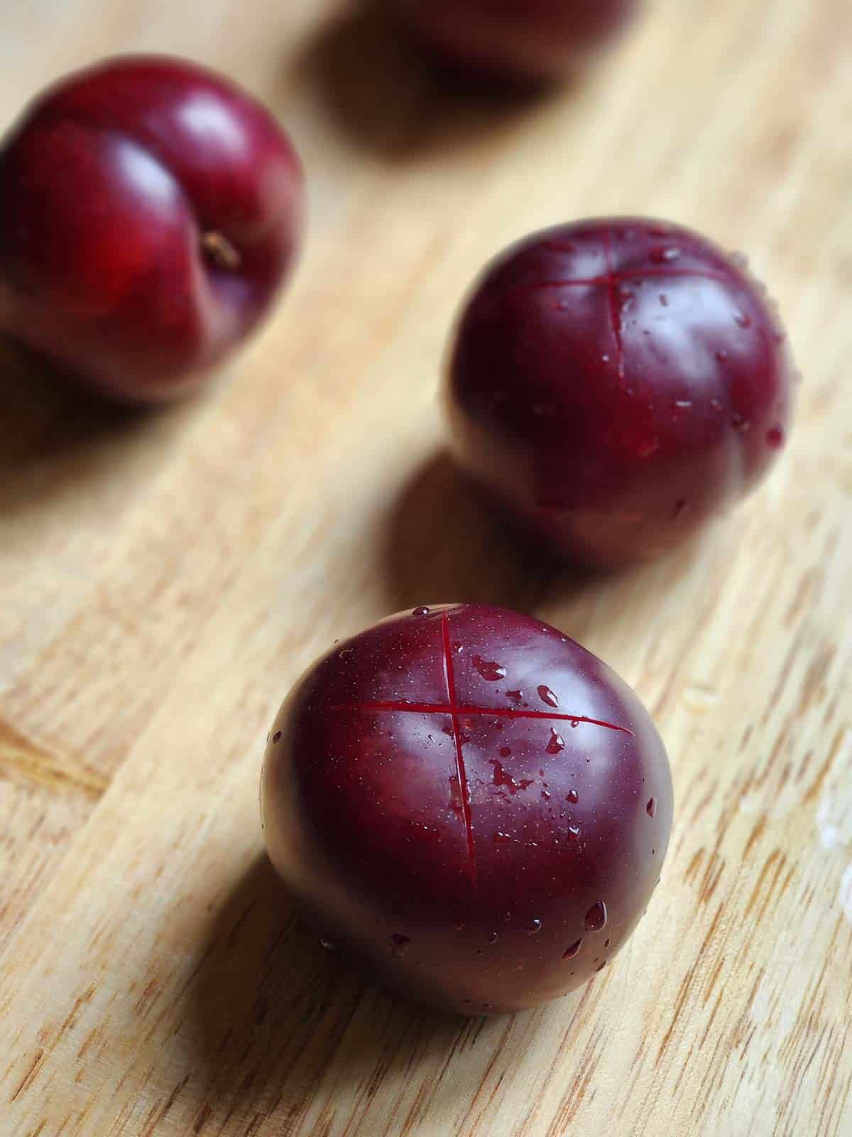 Plums with an "x" scored in the flesh.