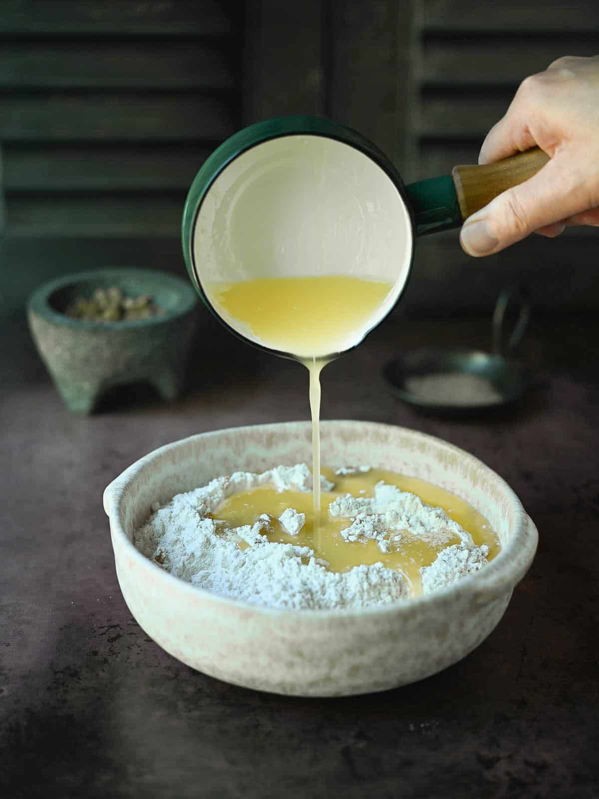 Butter being poured over flour and sugar for a streusel topping.