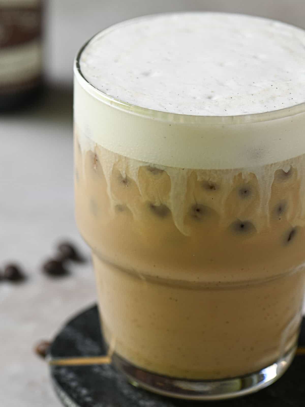 Close-up of milk and coffee mixed in a clear cup showing milk streaks.