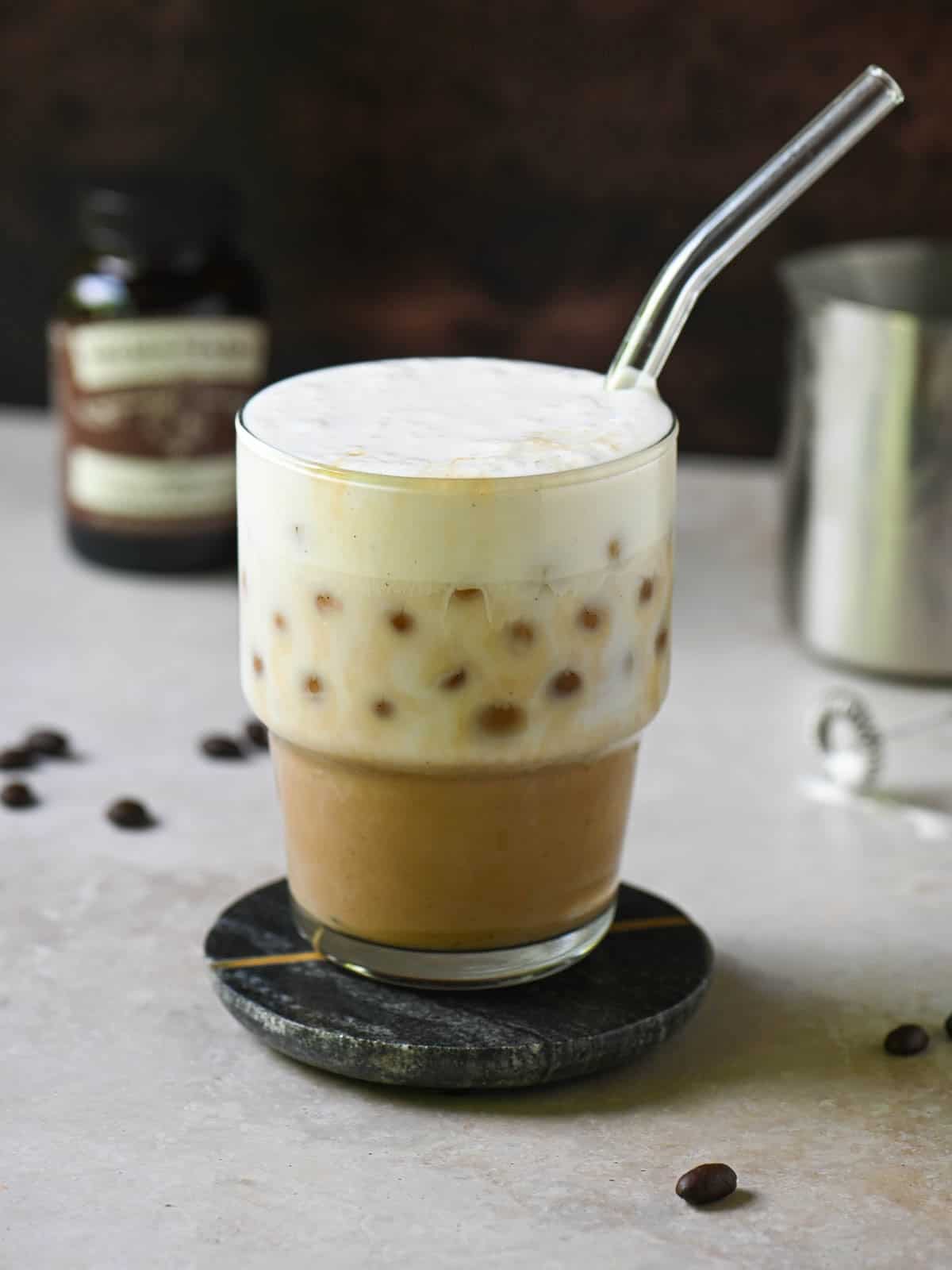 Eye-level view of a vanilla bean latte on a brown surface.