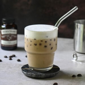 Eye-level view of a vanilla bean latte on a brown surface.