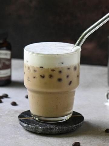 Eye-level view of a vanilla bean latte on a brown surface.