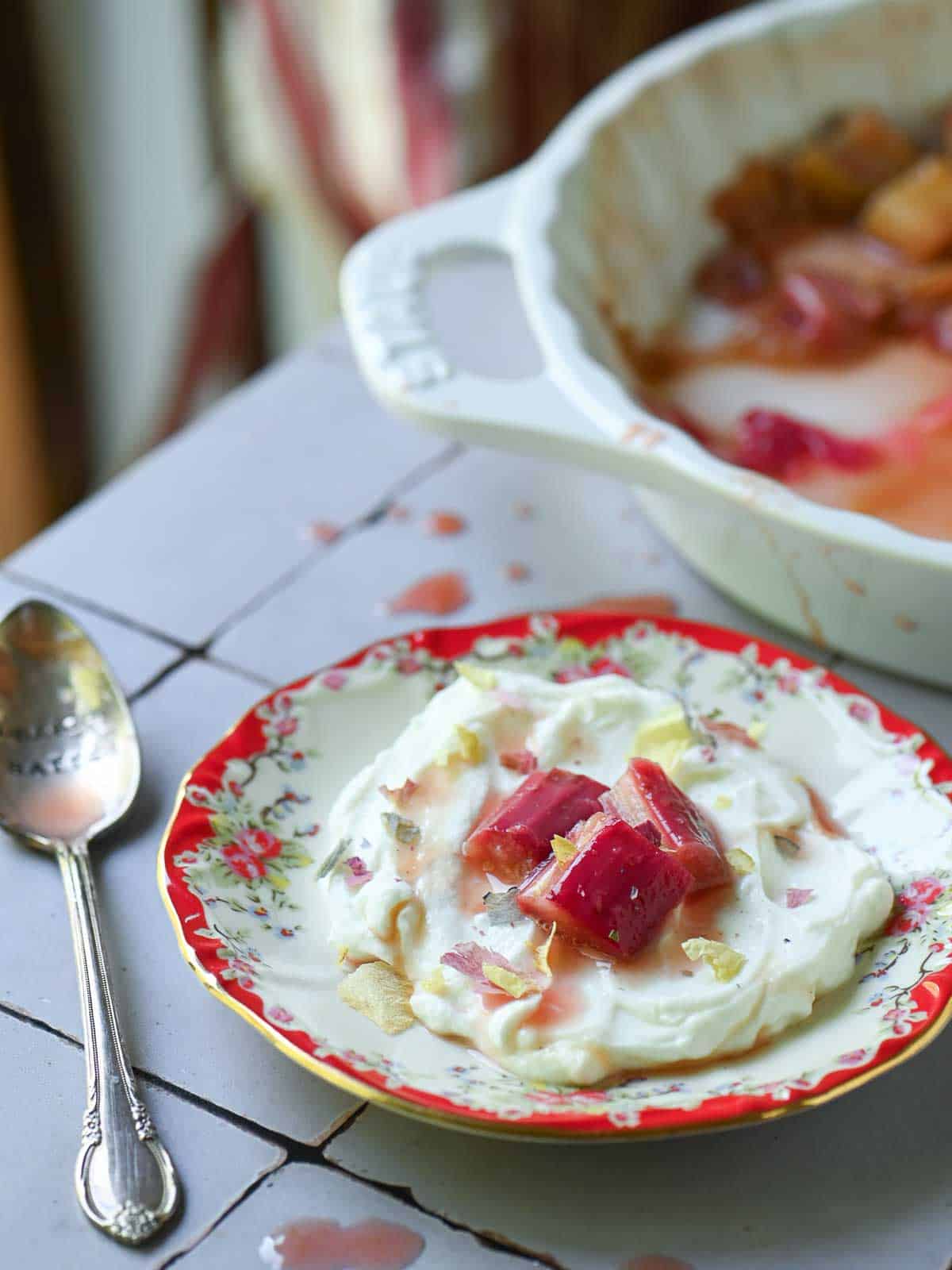 Yogurt with rhubarb compote on top in a red flowered dish.