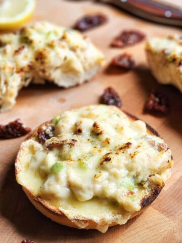 Tuna melt on a bagel on a wooden board.