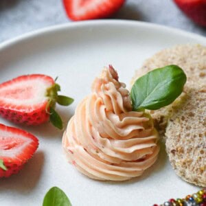Whipped strawberry butter on a white plate with basil in it.