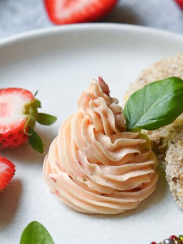 Whipped strawberry butter on a white plate with basil in it.