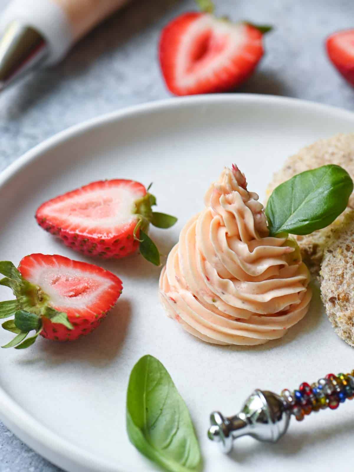Whipped strawberry butter in a white plate with strawberries.