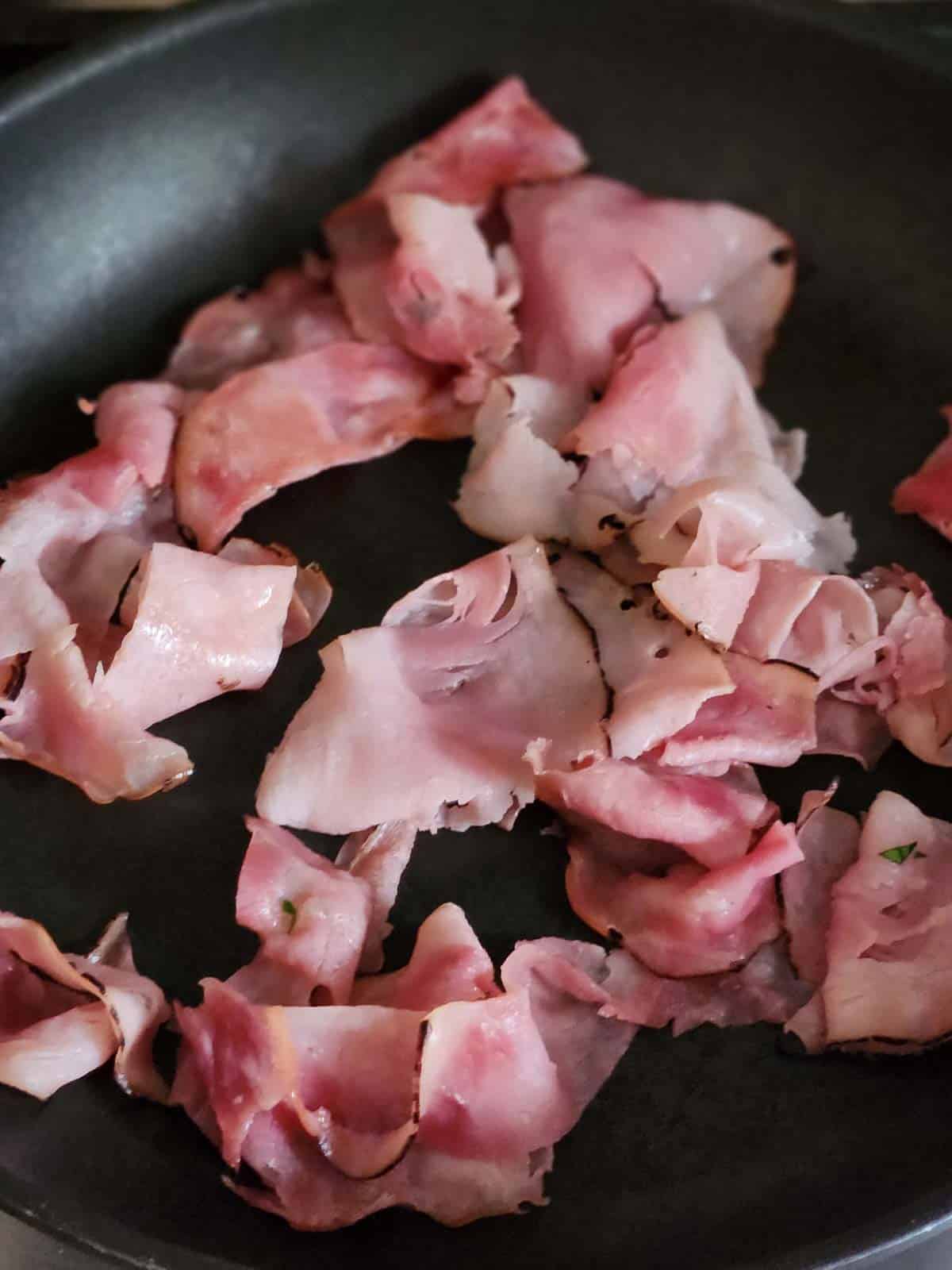 Crisped ham in a black skillet.