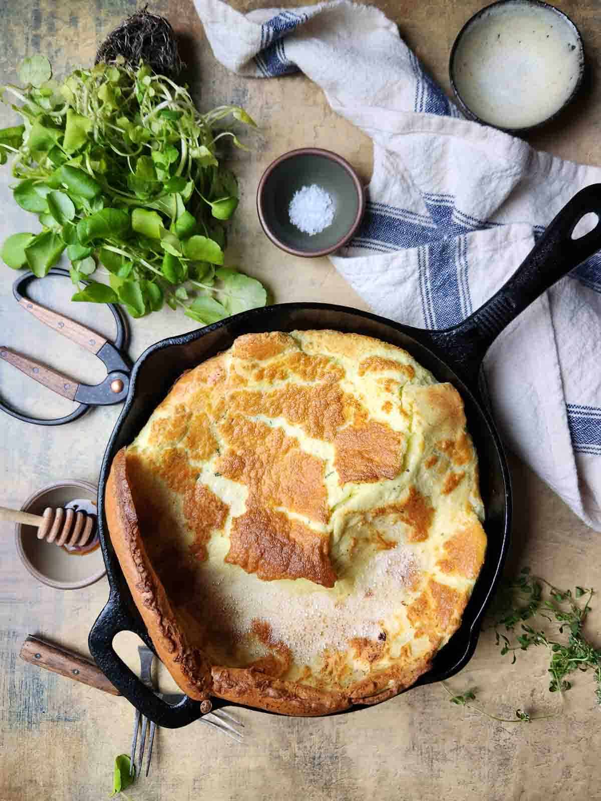 Overhead view of a cooked Dutch baby in a cast iron skillet.
