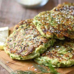 Zucchini pancakes on a wooden board with parmesan.