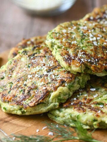 Zucchini pancakes on a wooden board with parmesan.