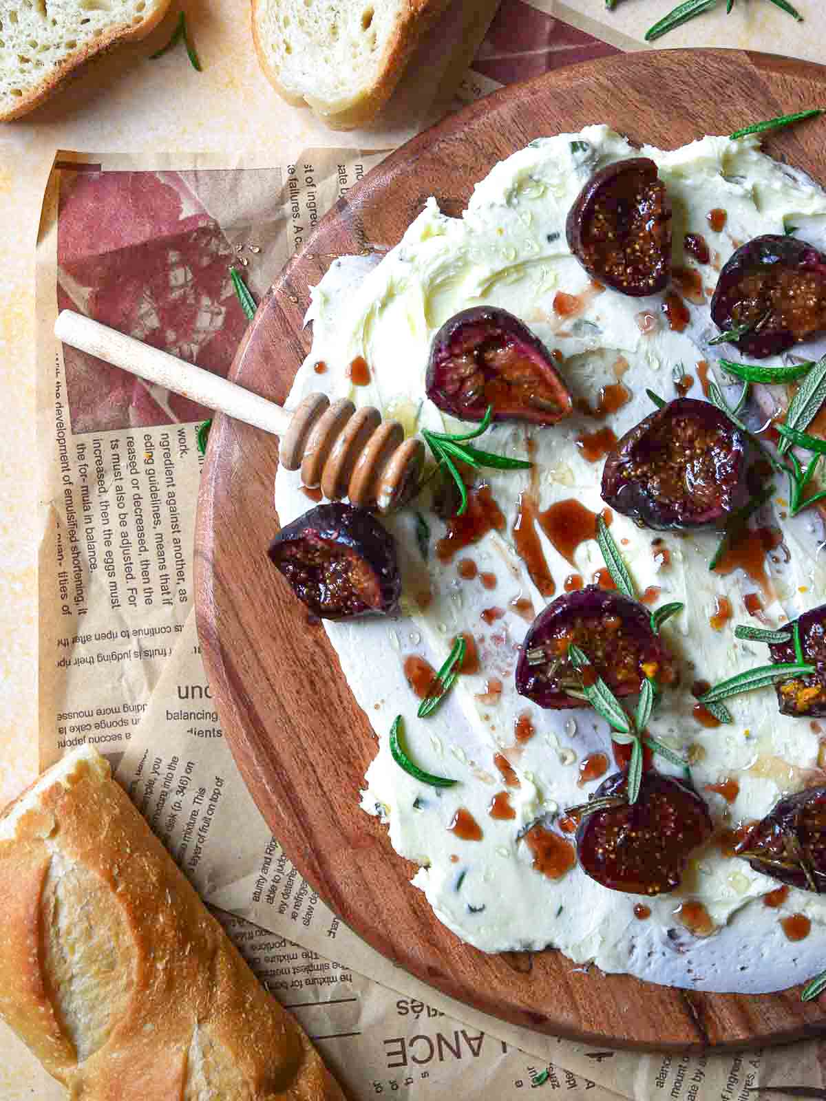 Figs and butter on a round wooden board with a honey stick.