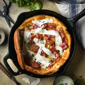 Overhead of a Savory Dutch baby with ham and cheese in a black skillet.