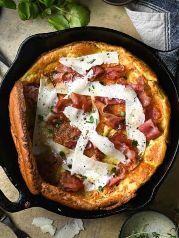 Overhead of a Savory Dutch baby with ham and cheese in a black skillet.