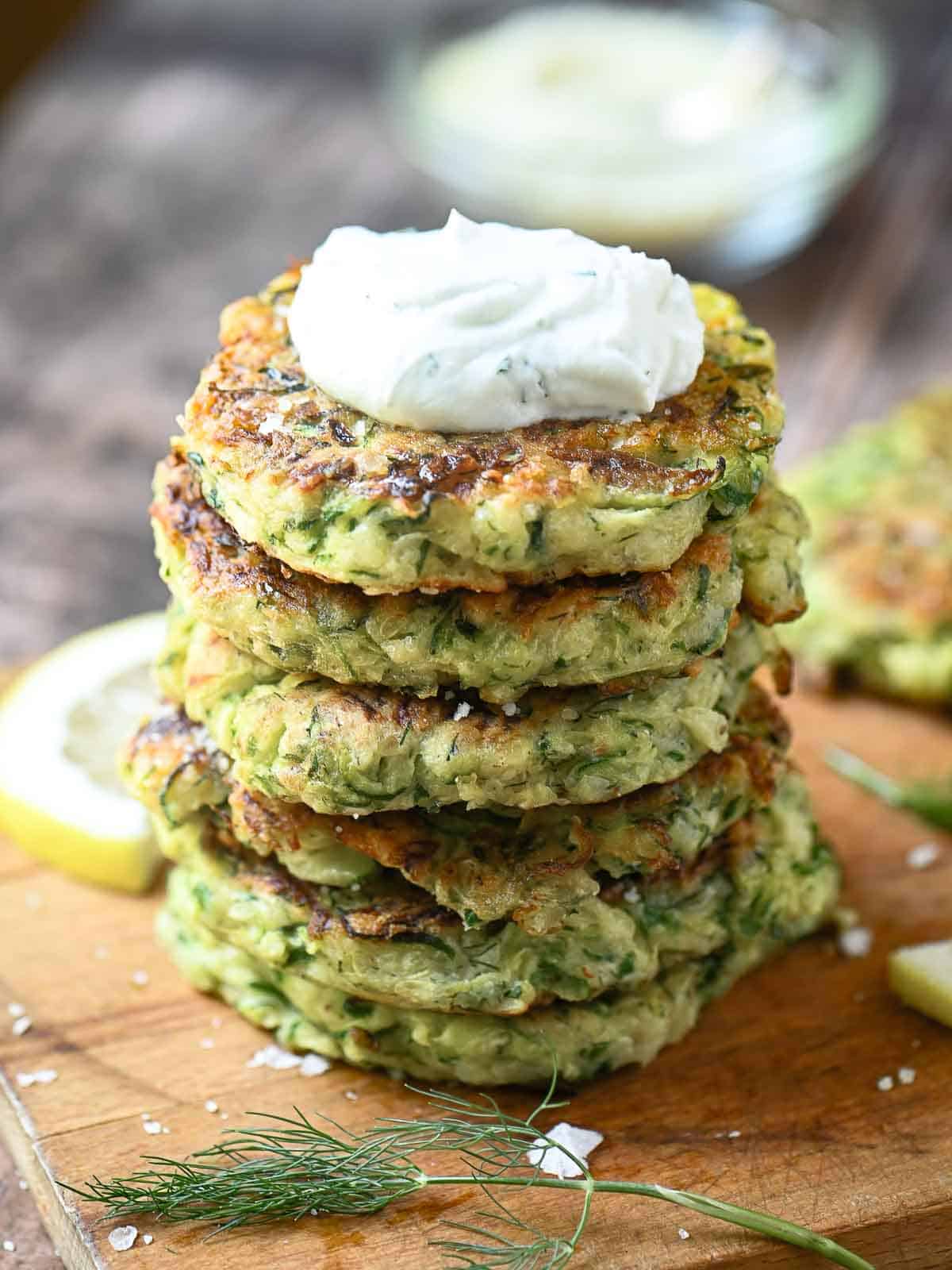 Stacked zucchini pancakes with a dollop of yogurt on top.