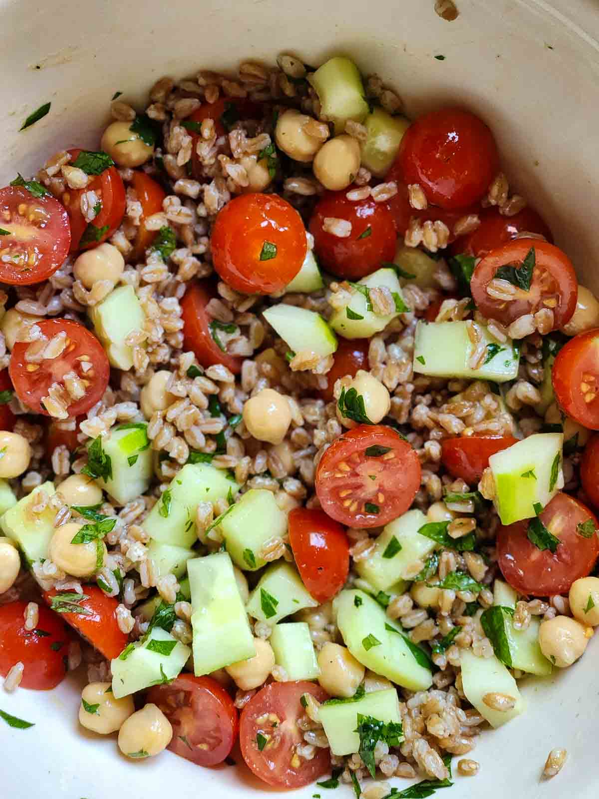 Overhead of farro salad in a bowl with tomatoes and cucumbers.