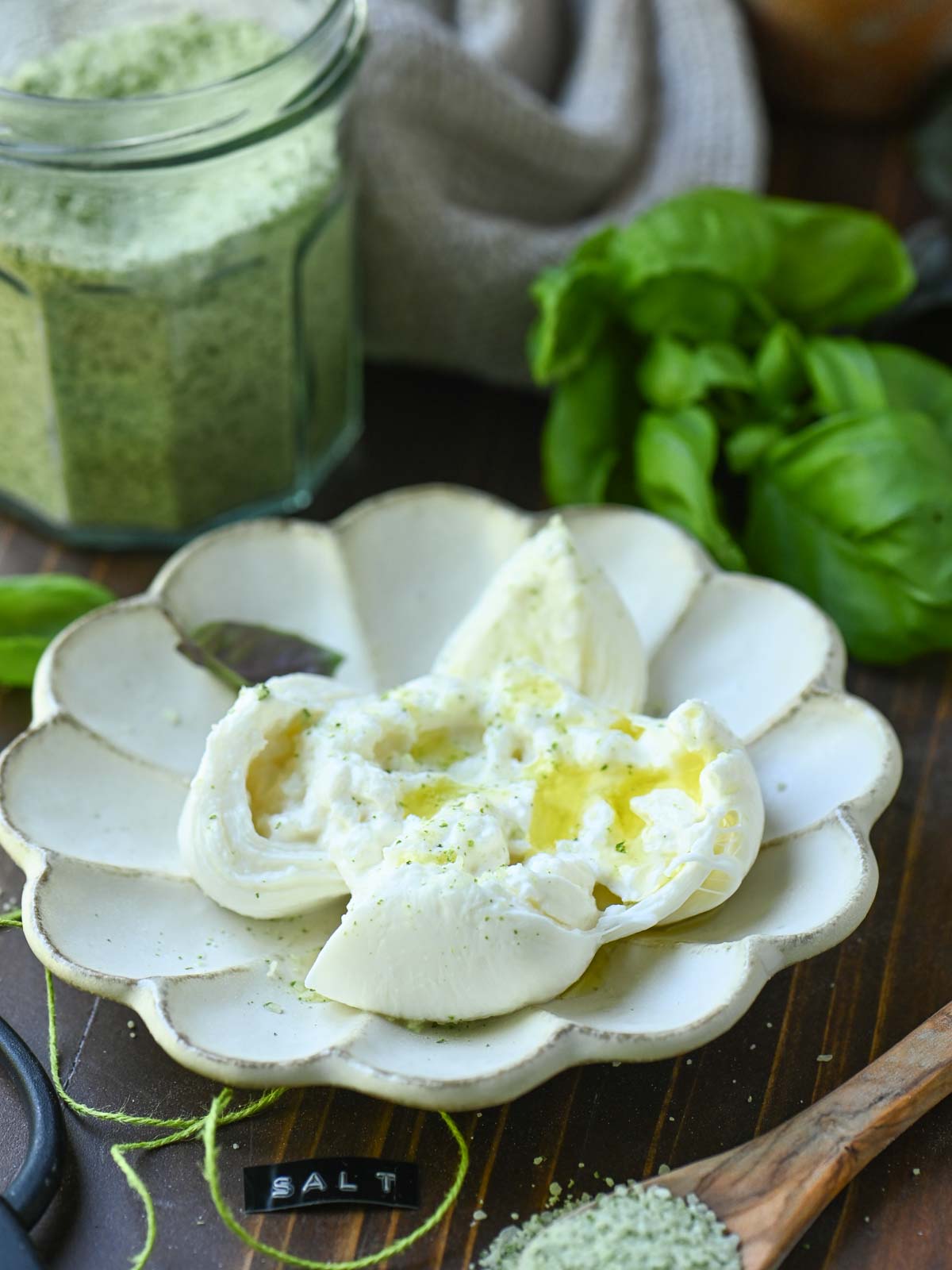 A plate of burrata cheese with oil and green basil salt.