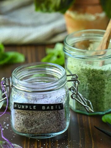 Two clear jars of purple and green basil salt.