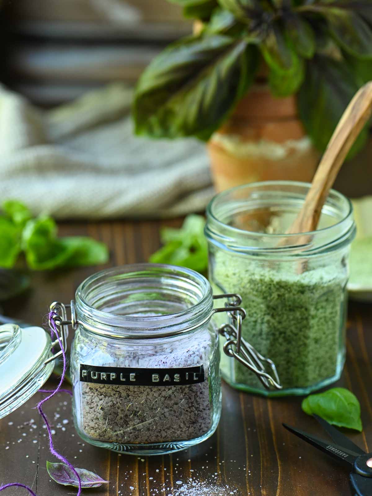 Two clear jars of purple and green basil salt.