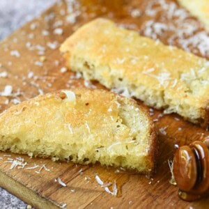 Close-up of 2 slices of Parmesan toast on a wooden board.