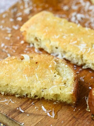 Close-up of 2 slices of Parmesan toast on a wooden board.