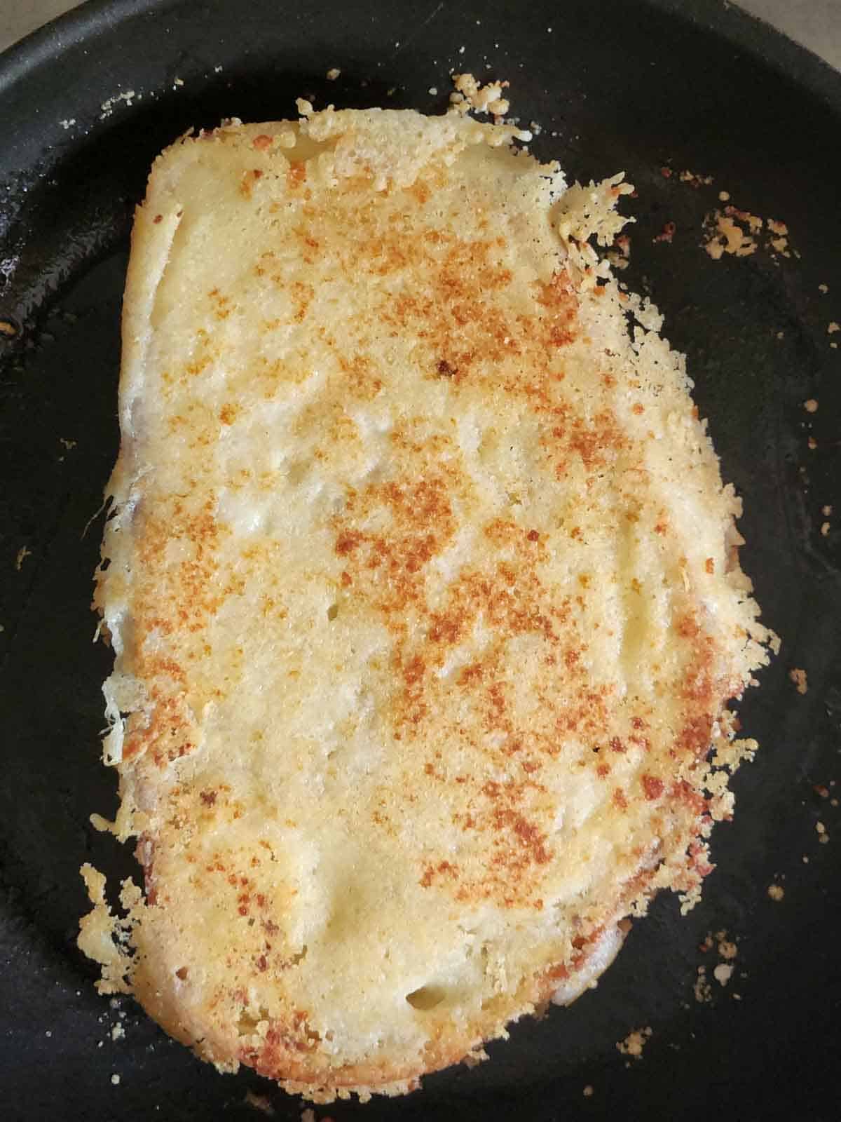 Parmesan crusted toast in a black skillet.