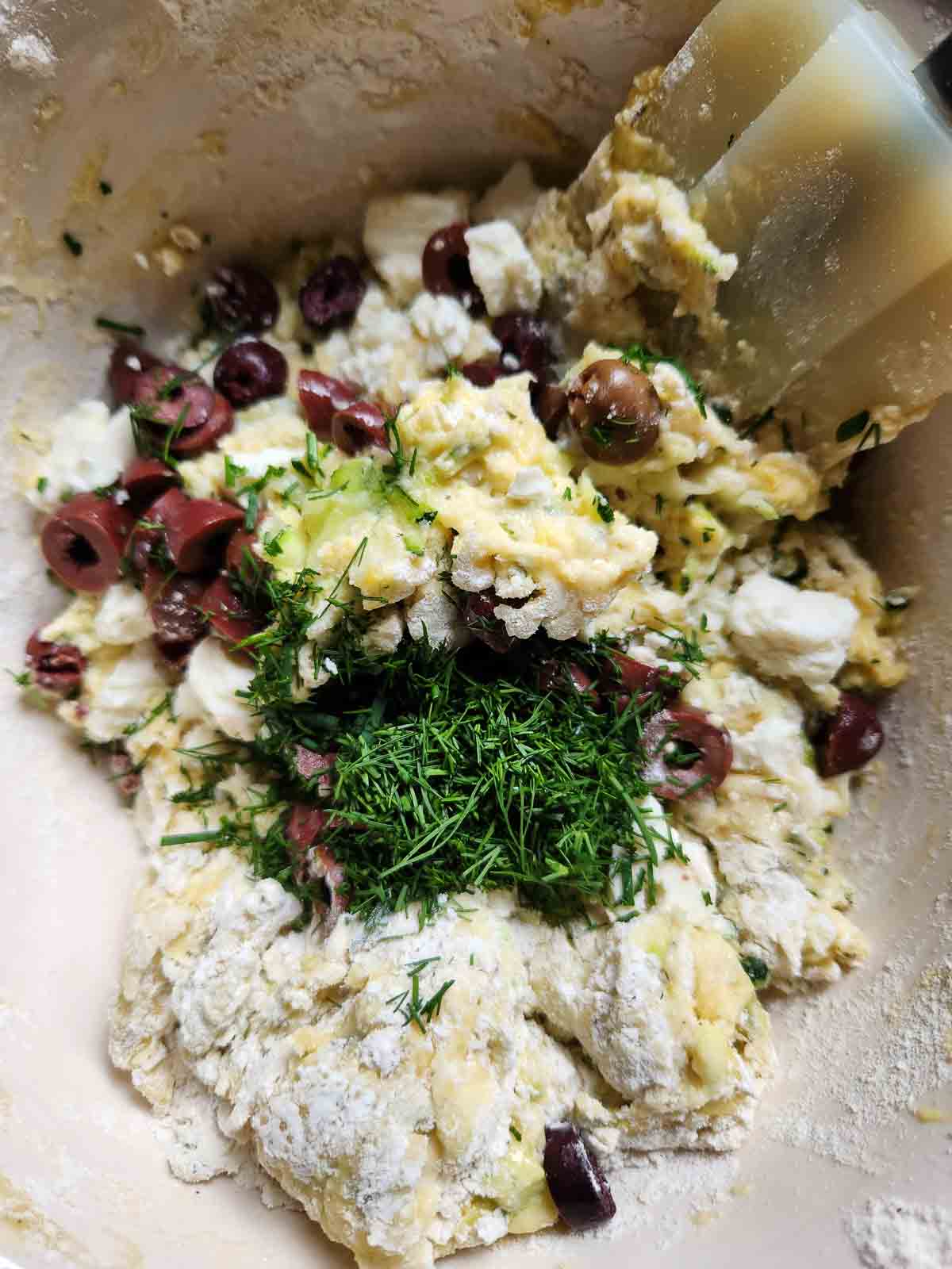 Batter for zucchini bread in a bowl with a spatula.