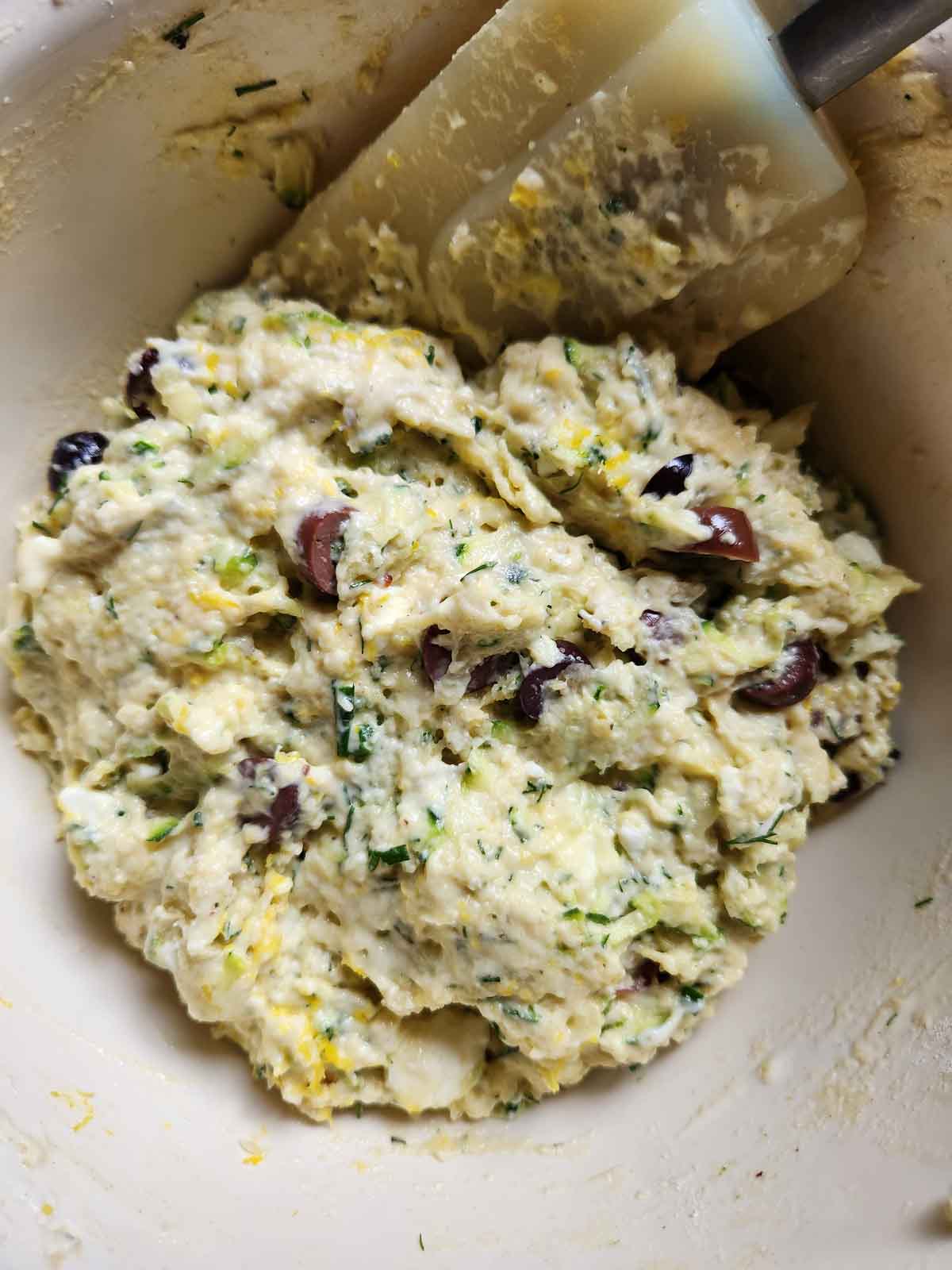 Mixed zucchini batter in a bowl with a spatula.