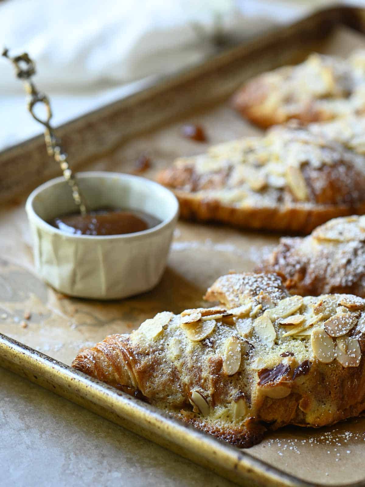Almond croissants and apple butter on a baking tray.