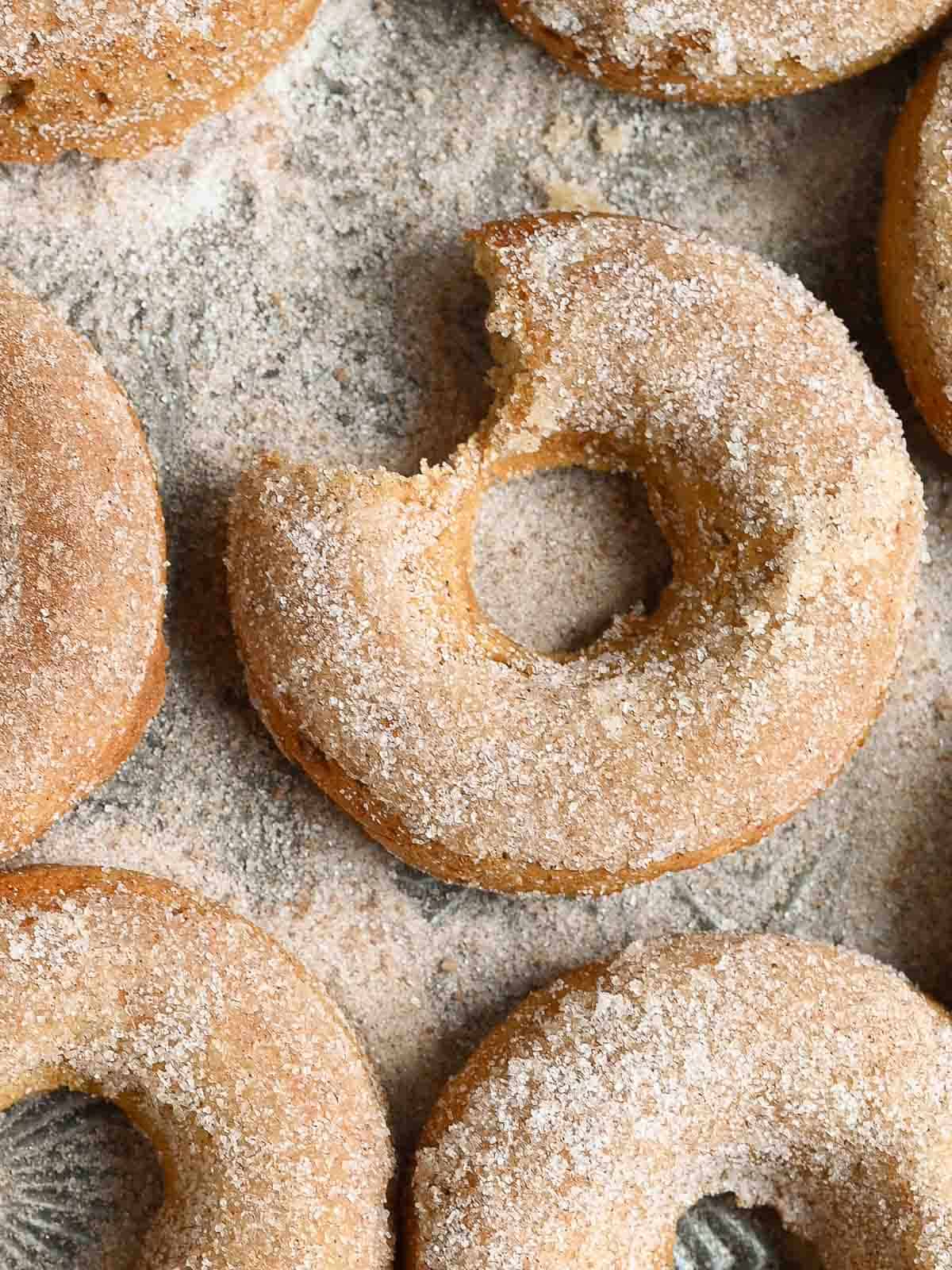 A bite of an apple donut taken out on a tray.