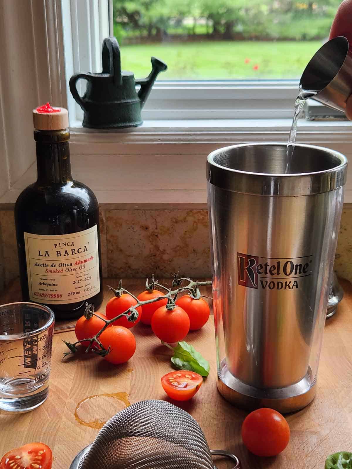 Vodka is being poured into a cocktail shaker on a wooden board with other cocktail ingredients.