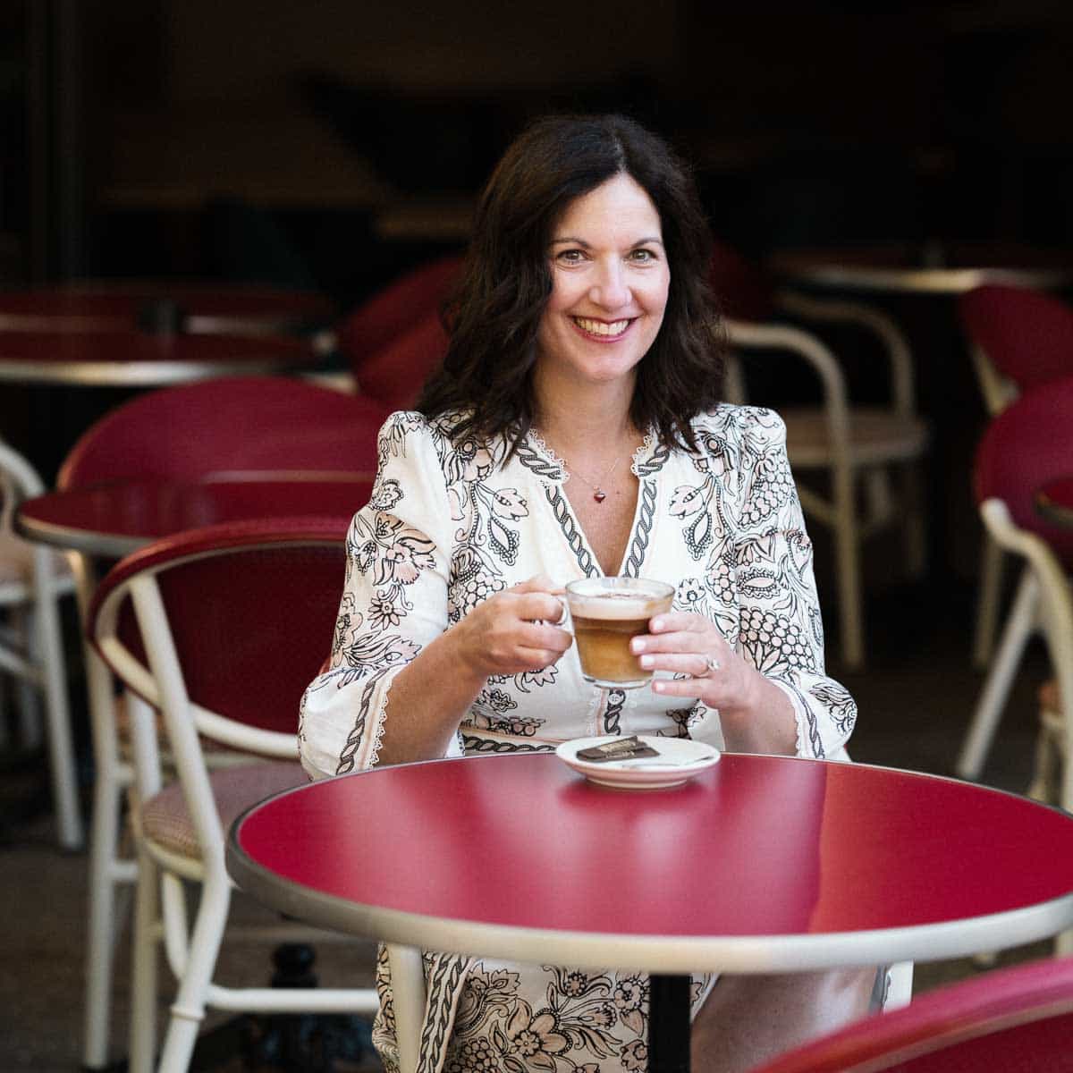 The author sitting at a red table drinking coffee.